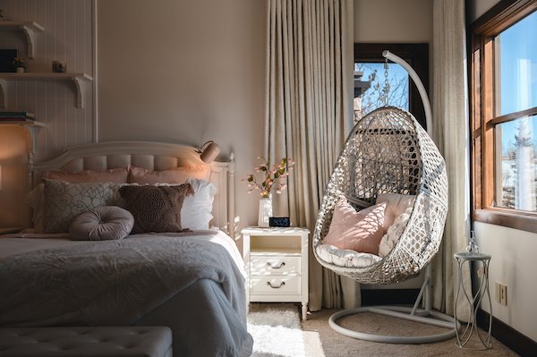 cozy girls room with swinging chair and comfy bedding