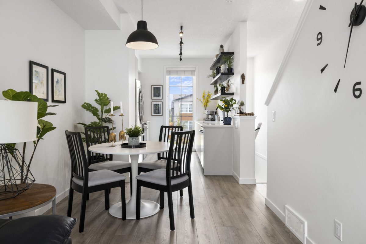 a small round table to optimize space with black accents surrounding the space and plenty of plants