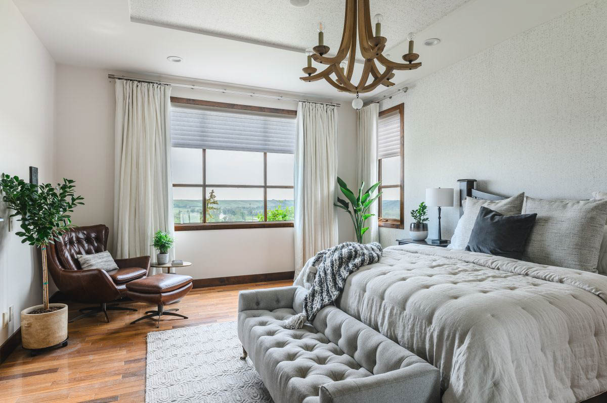 a gorgeous neutral master bedroom utilizing plants and brown leather chair