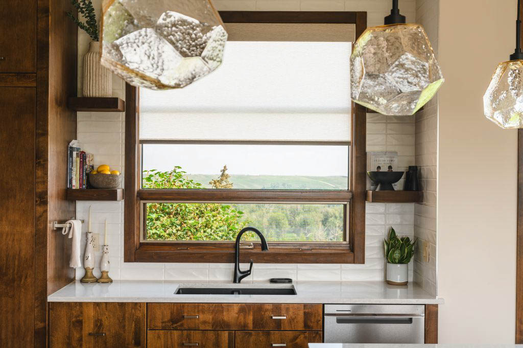 beautiful pendant lights hanging over the kitchen island with a picturesque landscape view from the sink