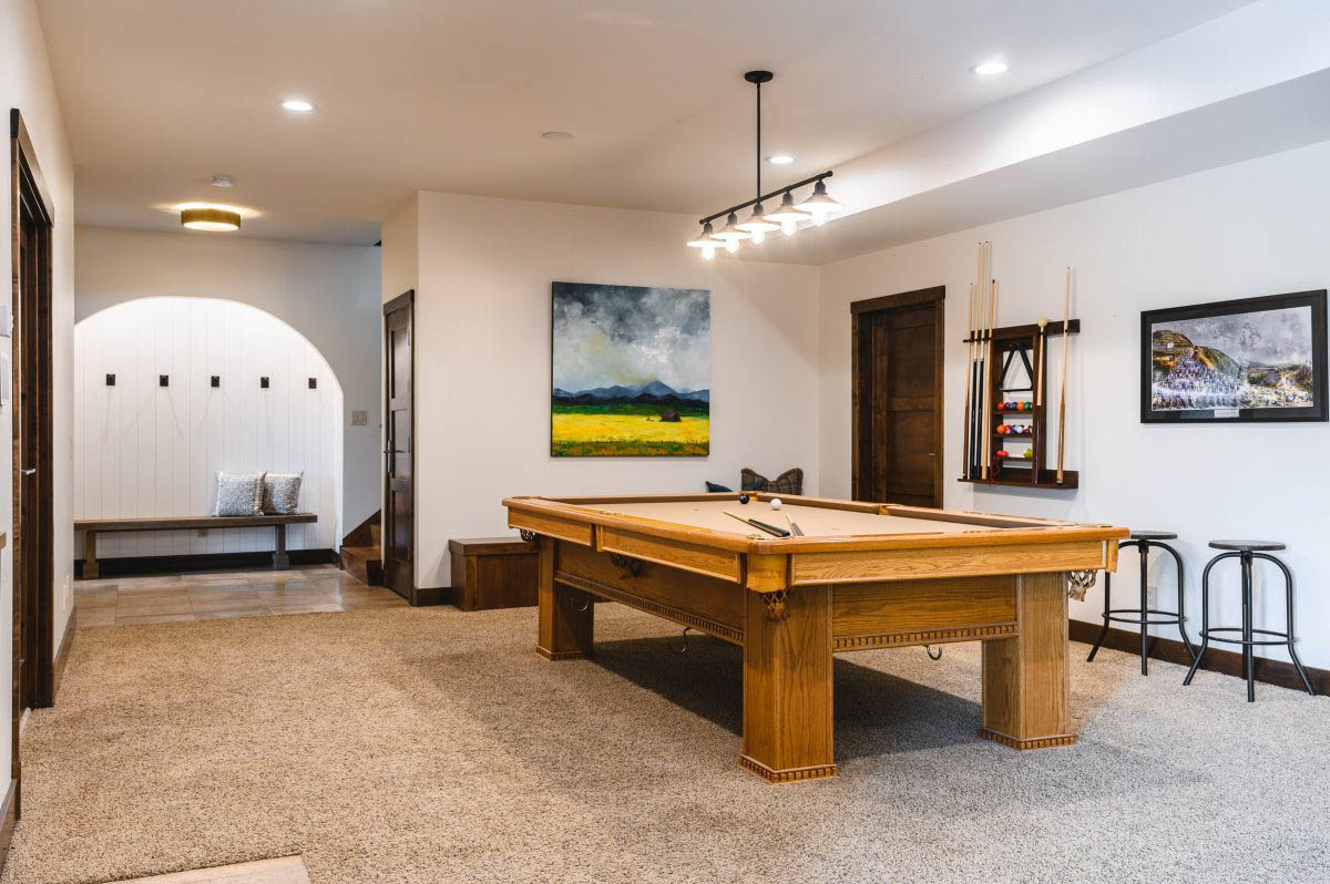 a family area with a pool table, pool que, and stools for entertaining, as well as a bench for additional seating