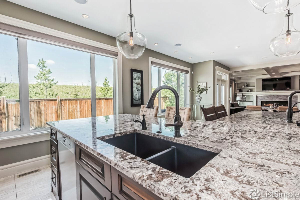 modern kitchen with brown quartz countertops to accent the walls and cabinetry. two simple pieces of artwork to highlight to windows