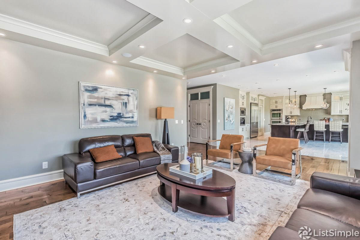 the brown and orange furniture was styled properly with a blue and grey painting to match the walls and other decor, as well as a large grey area rug. the coffee table styled perfectly with a tray, candle and decor