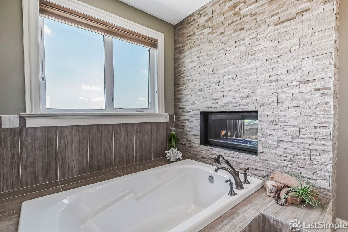 this master bathrooms bathtub was styled with organic decor including a shell, towels, plants, and containers for soap and more