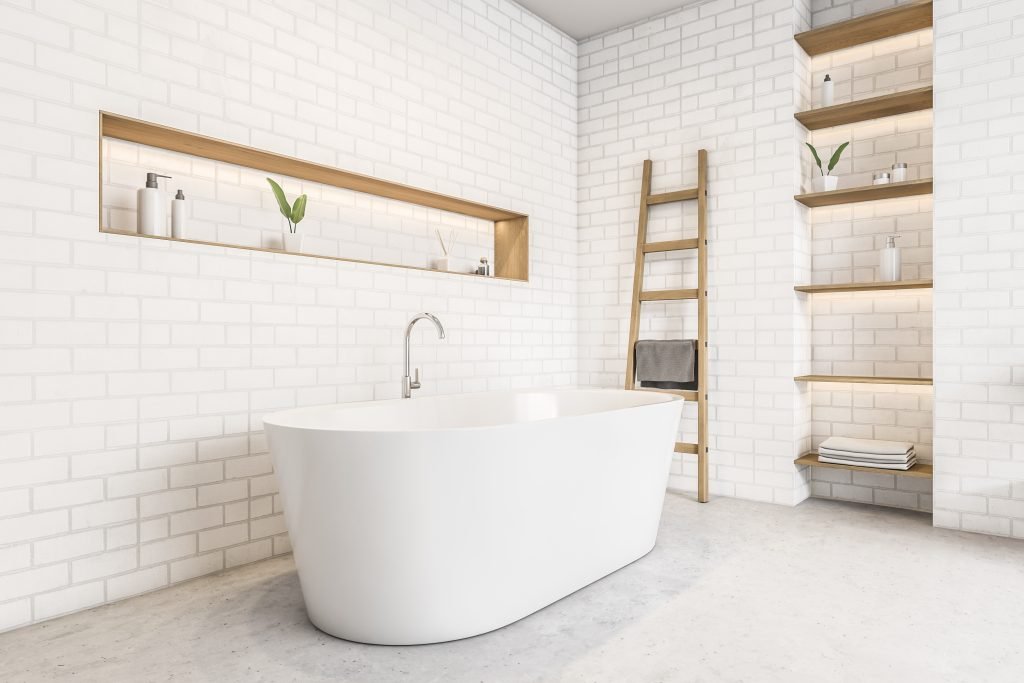 White bathtub and brick wall, shelves with gels and plants, marb