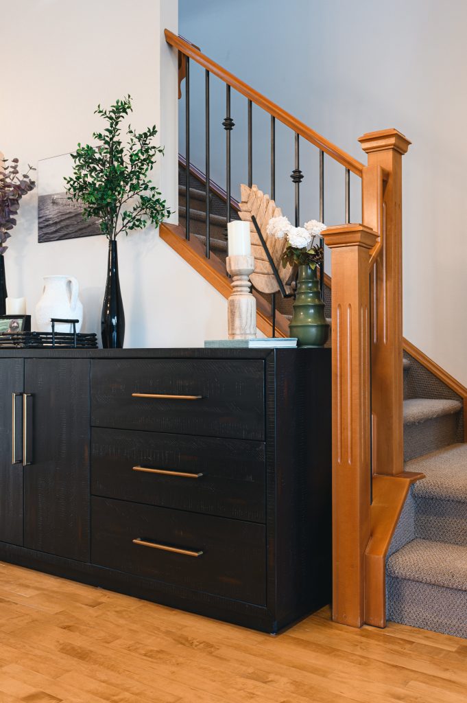 Cozy luxury killarney home interior decorating Entry Way light wood railing unshelf design. Black console table with modern tall vase styled with white, wood and green decor.