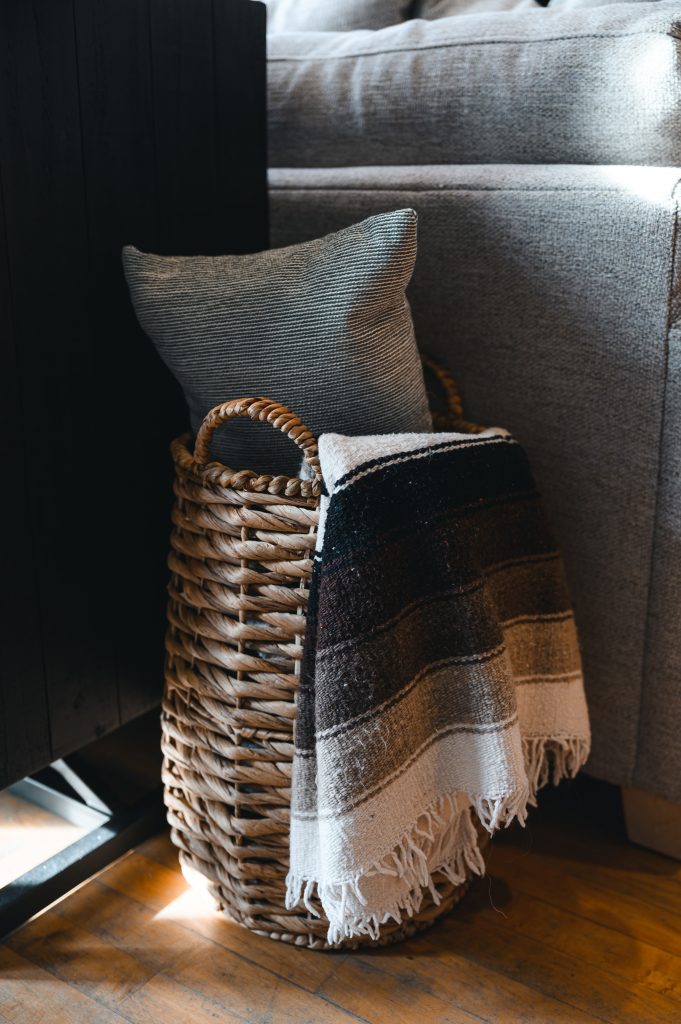 Cozy luxury killarney home interior decorating Living Room wood detail unshelf design. Woven basket styled with a grey, black and white striped throw blanket.
