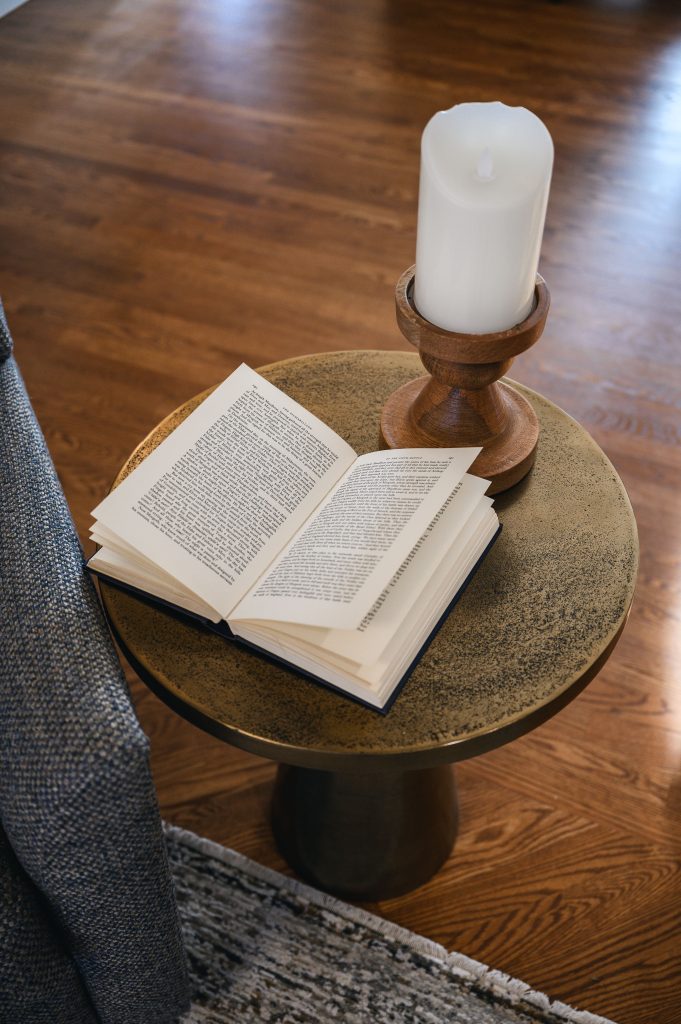 Tuscany Estate Interior Decorating Living Room Side Table Unshelf Design. Aged brass side table with a candle stick and open book.
