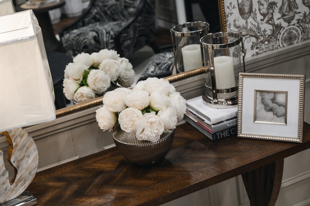 Renovation Show Stately Room Interior Decorating Stately Details of Modern Decor Unshelf Design. Console table details with a picture frame and a vase holding white flowers.