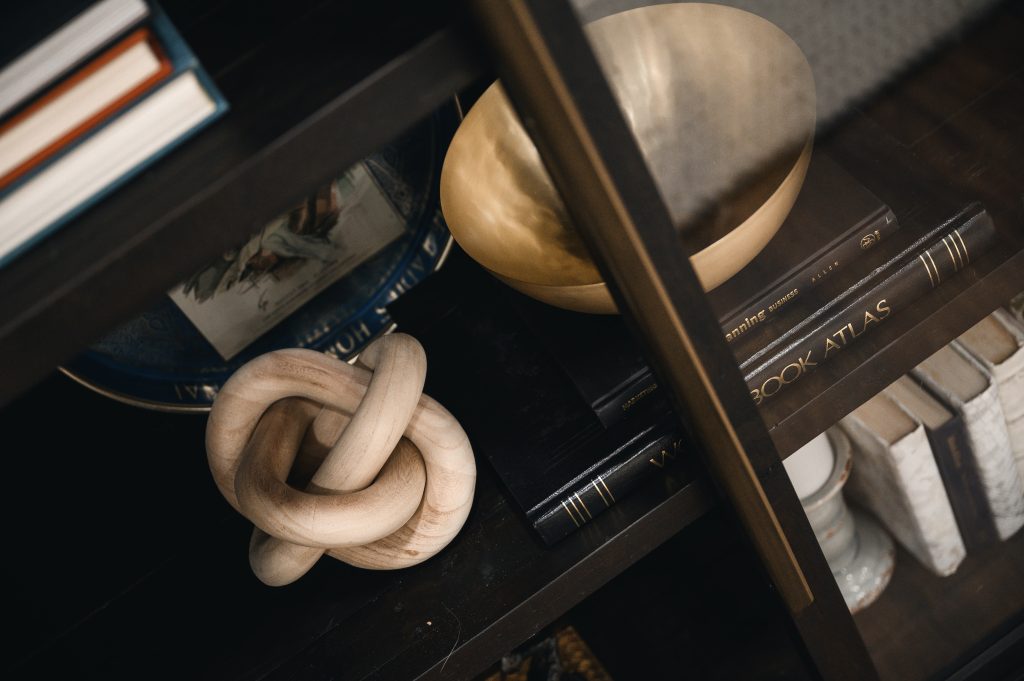 Renovation Show Stately Room Interior Decorating Stately Shelfie Textured Wood Knot Unshelf Design. Gold decorative bowl sitting on top of a stack of books.