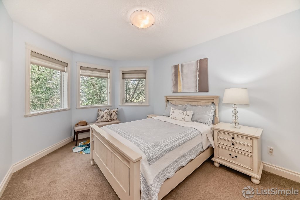Transitional Inglewood Home Home Staging Guest Bedroom 1 Blue Bedding Unshelf Design. Large guest bedroom with grey roman shades and grey and gold abstract artwork.