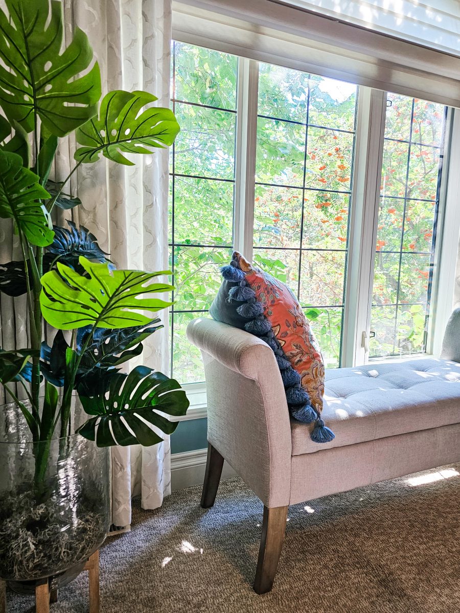 Transitional Inglewood Home Home Staging Living Room Bench with Floral Throw Pillow Detail Unshelf Design. Large window in front of an off-white bench with a large floral cushion.