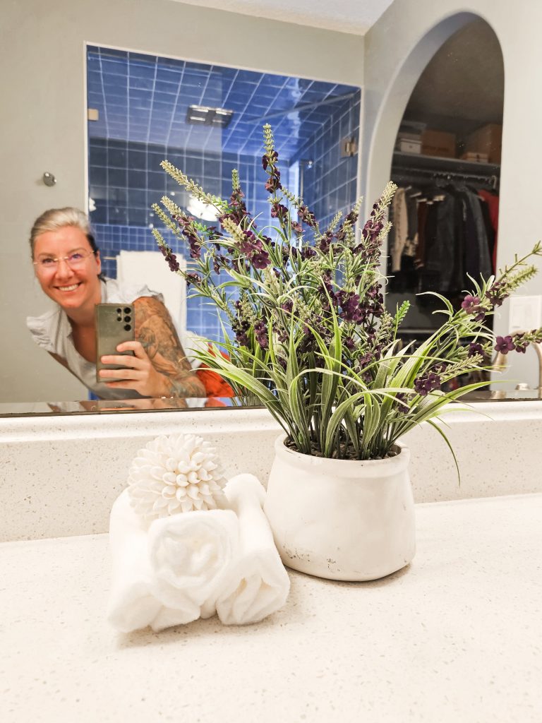 Transitional Inglewood Home Home Staging Primary Bathroom Plant and Towel Detail Unshelf Design. White towels styled with modern purple plant decor.