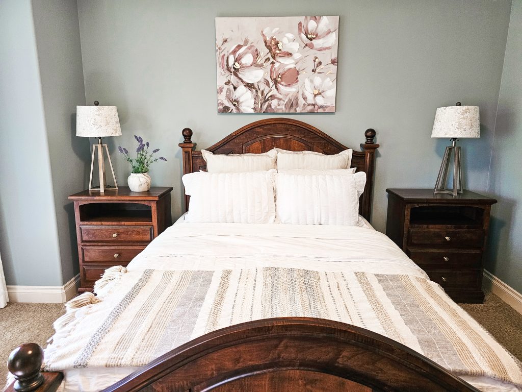 Transitional Inglewood Home Home Staging Primary Bedroom Floral Artwork Unshelf Design. Queen bed with dark wood frame and neutral striped bedding.