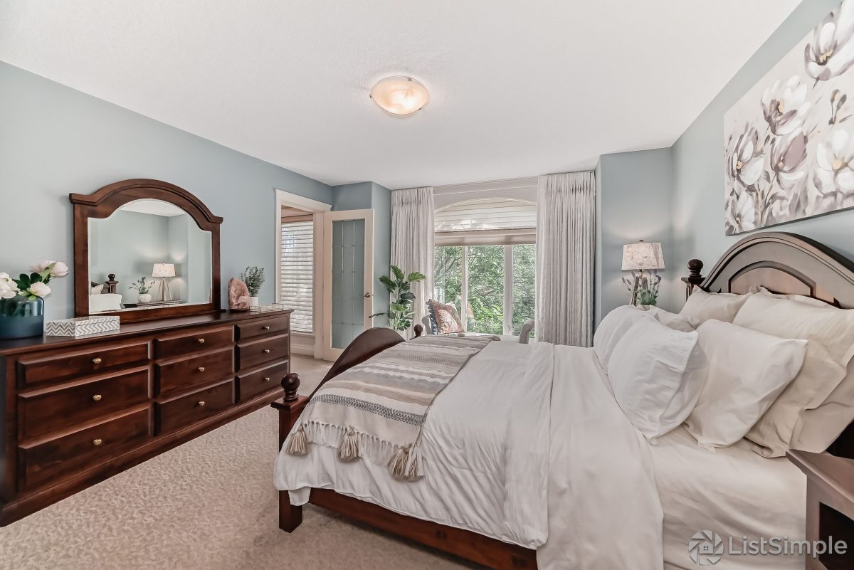 Transitional Inglewood Home Home Staging Primary Bedroom Floral Artwork Unshelf Design. Queen bed with dark wood frame and neutral striped bedding.