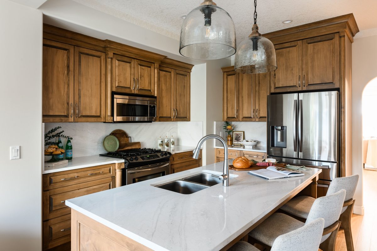 modern kitchen with brown quartz countertops to accent the walls and cabinetry. two simple pieces of artwork to highlight to windows