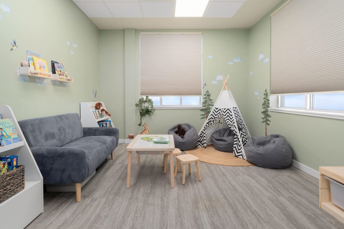Psychology clinic commercial decorating jungle playroom by Unshelf Design. Green jungle playroom with grey couch and bean bag seating.