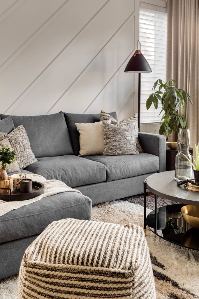 Grey L-shaped couch with lighter accent pillows. Modern mountain design interior furnishing & decorating grey and white living room Unshelf Design