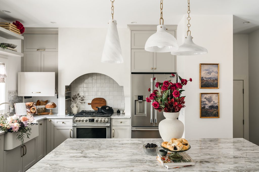 Red bouquet and decor on large marble kitchen island with the bright kitchen in the background.