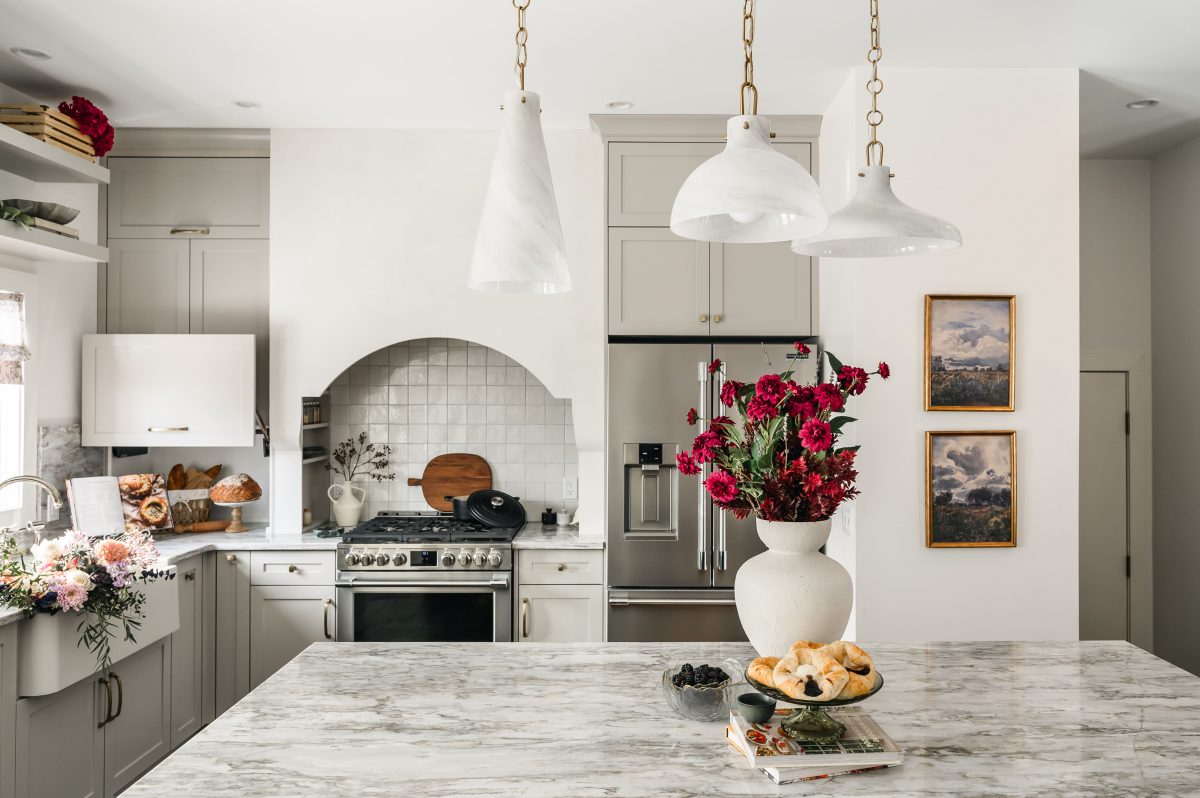 Red bouquet and decor on large marble kitchen island with the bright kitchen in the background.