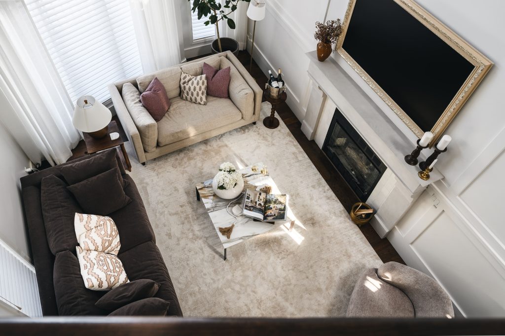 Overhead view of the living room layout with neutral sofas, a marble coffee table, and a fireplace on a neutral rug.