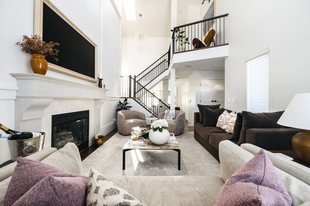 Living room with a tiled fireplace, lilac and neutral throw pillows, and a staircase leading to the upper level.