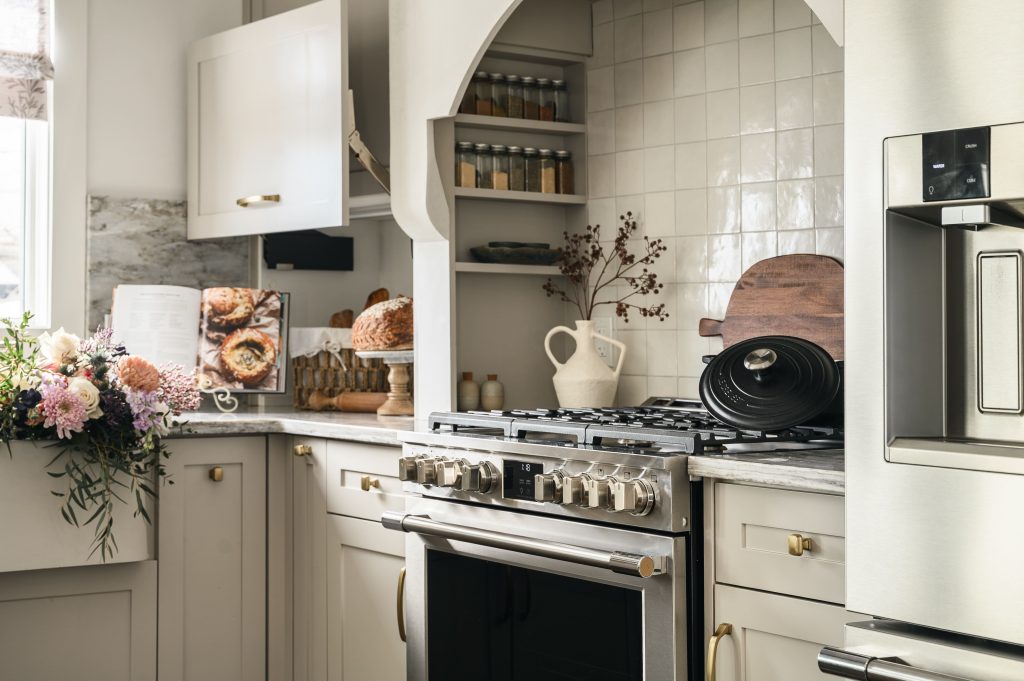 Victorian kitchen range styled with a cast iron Dutch oven, wooden cutting board, and a white pitcher with dried botanicals.