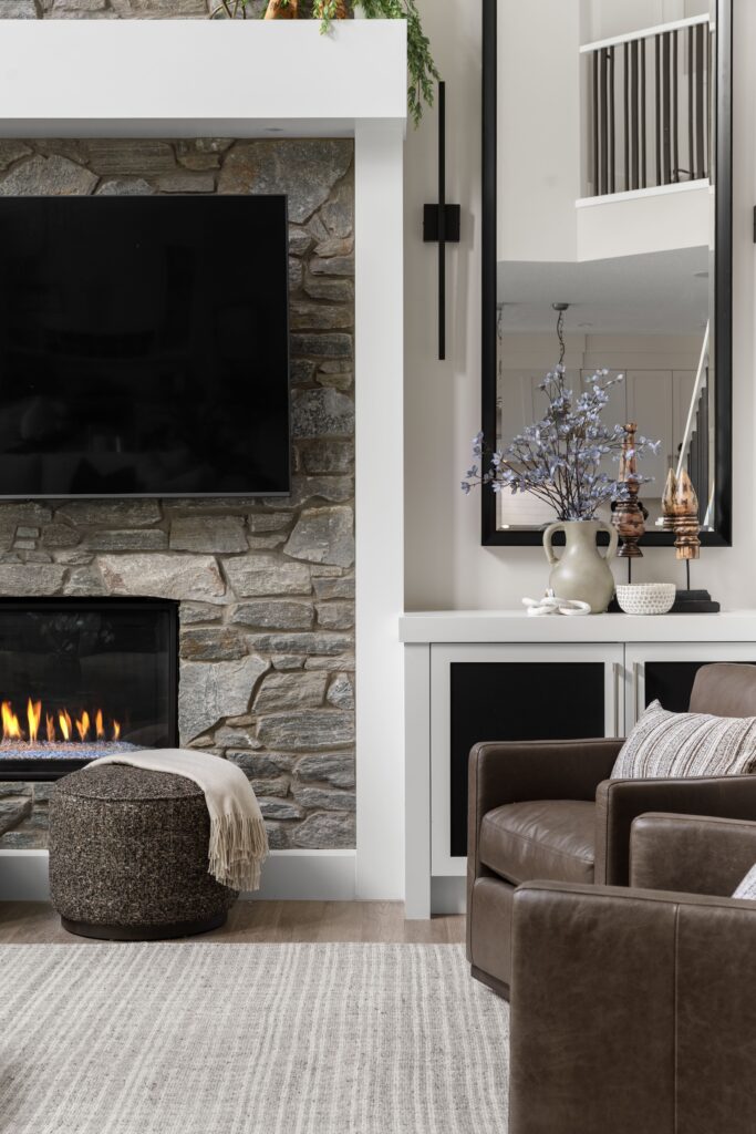 A styled built-in console beside the fireplace holds a vase of blue florals, wooden decor, and a patterned bowl.