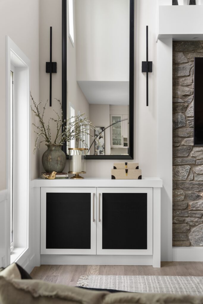The built-in console, styled with a willow arrangement, reflects the dining room in the mirror hung above.