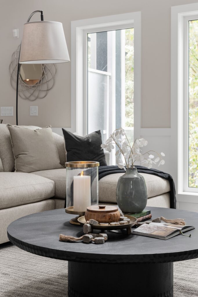 The coffee table is styled with a candle, wooden lidded dish, ceramic vase, and a garland of stone beads.