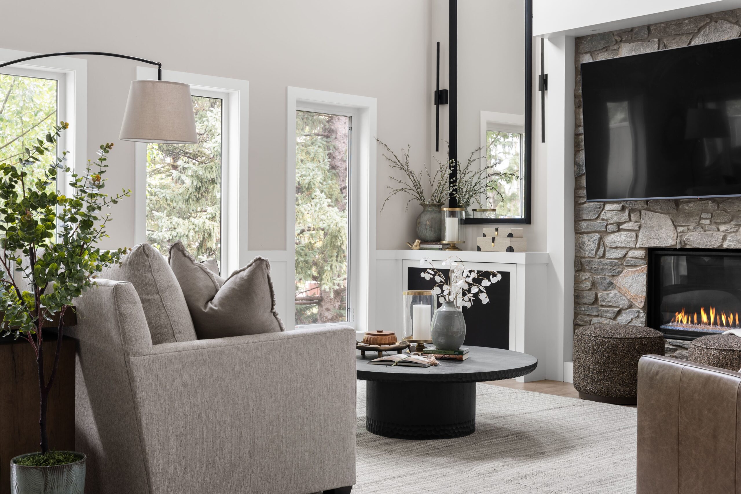 A sectional sofa, armchair, and arched floor lamp anchor this family room seating area, with the fireplace glowing in the background.