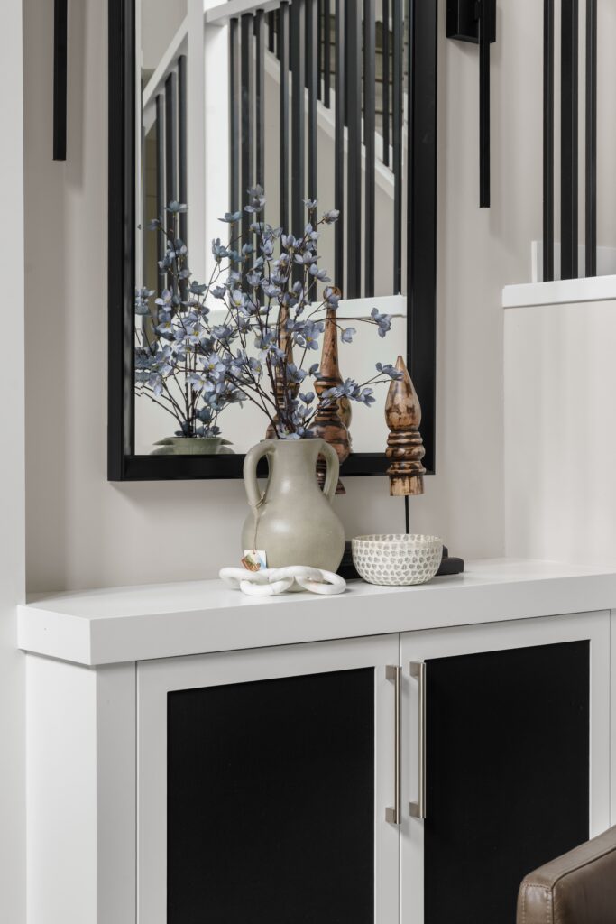Built-in console styling vingette, complete with a vase of blue florals, wooden decor, and a patterned bowl.
