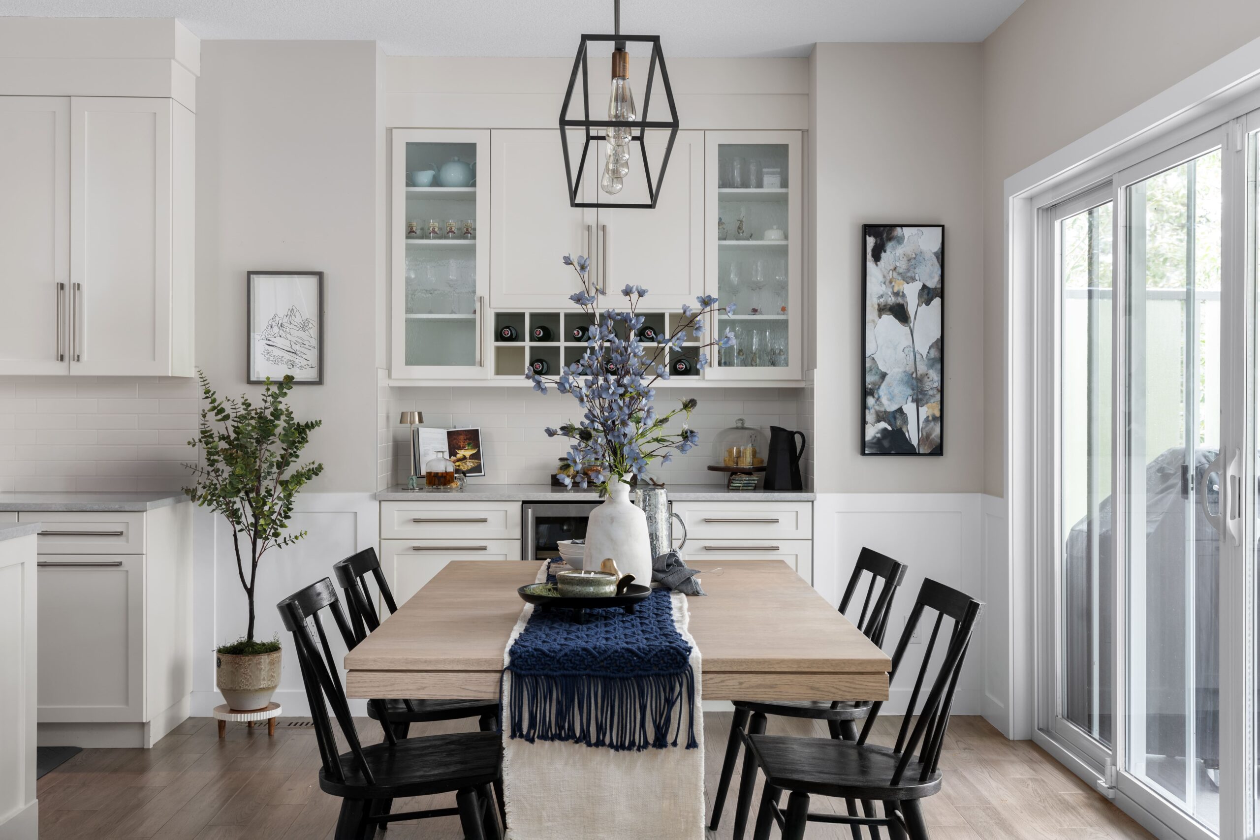 An open dining space with black dining chairs, a geometric pendant light, and a wine bar along the far wall.