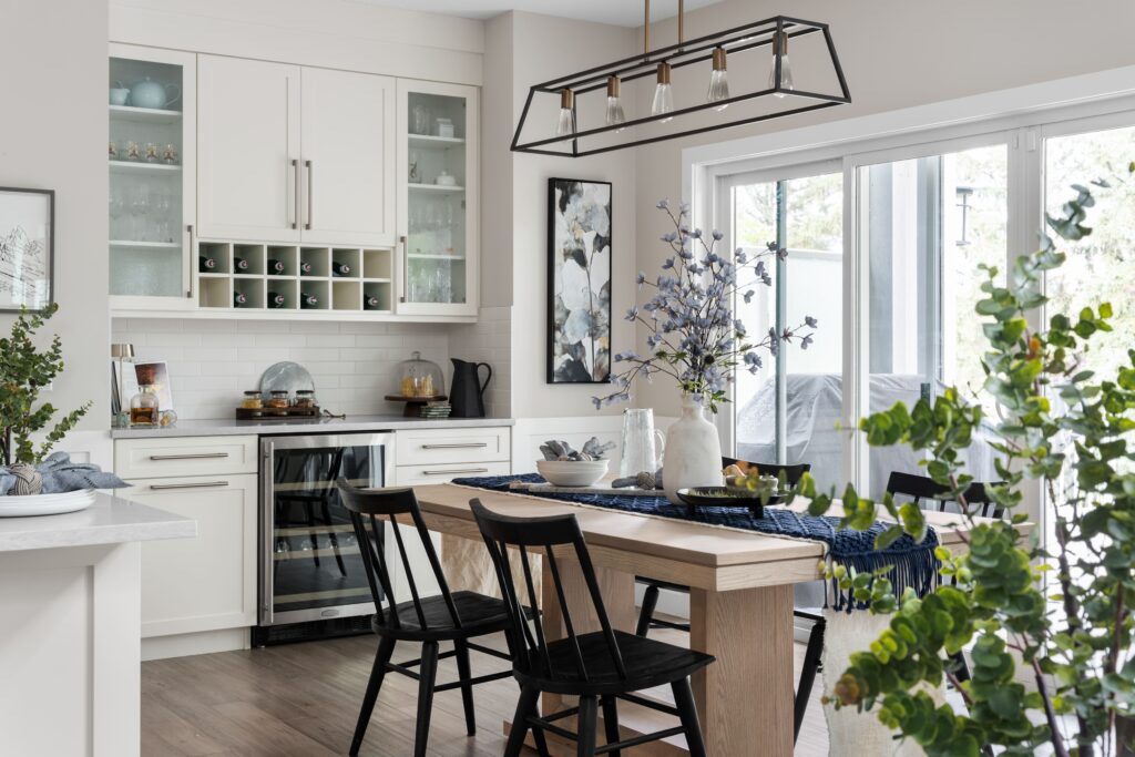A view of the dining room, just off the kitchen. Styled with a potted tree, framed art, and a wine bar set for entertaining.