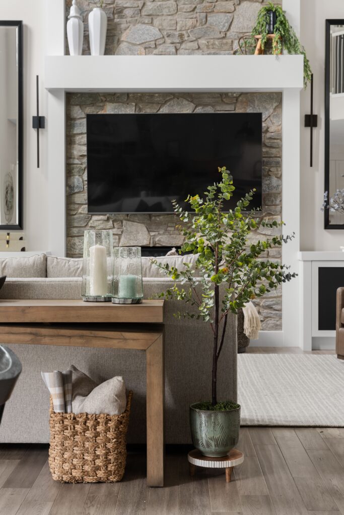 A potted tree stands beside the console table, which is styled with candle holders and a woven storage basket.