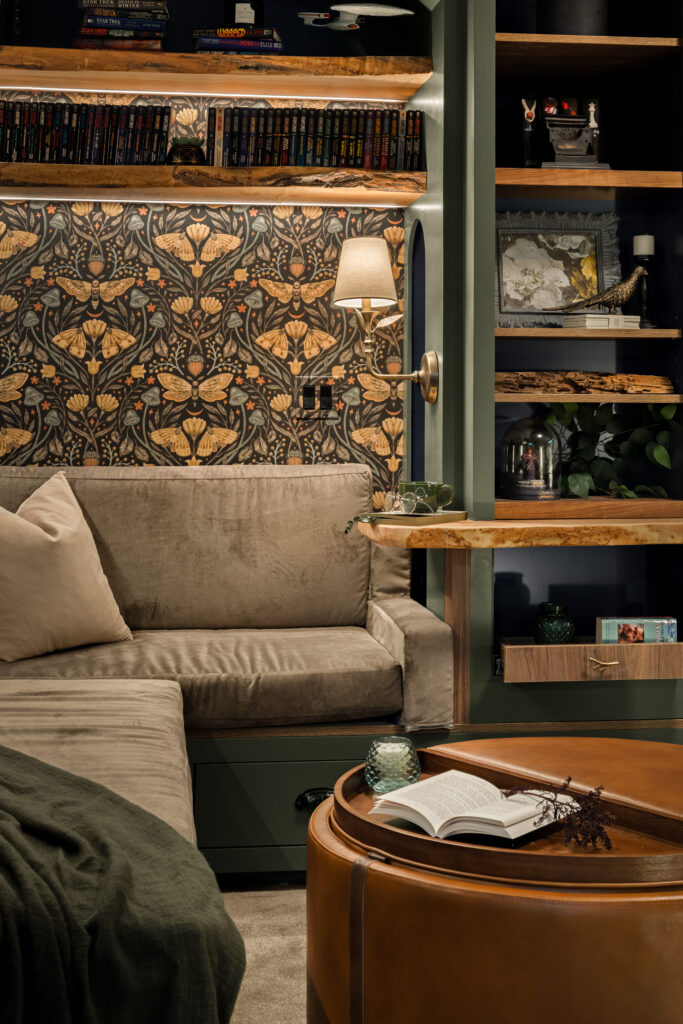 Built-in shelving filled with a paperback collection, framed art, and decor beside a cozy reading nook.