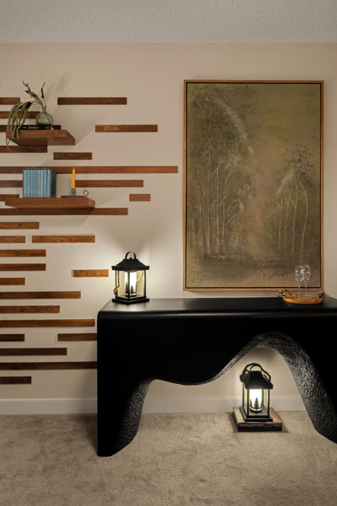A sculptural black concrete console table paired with a wood slat accent wall and framed nature artwork.
