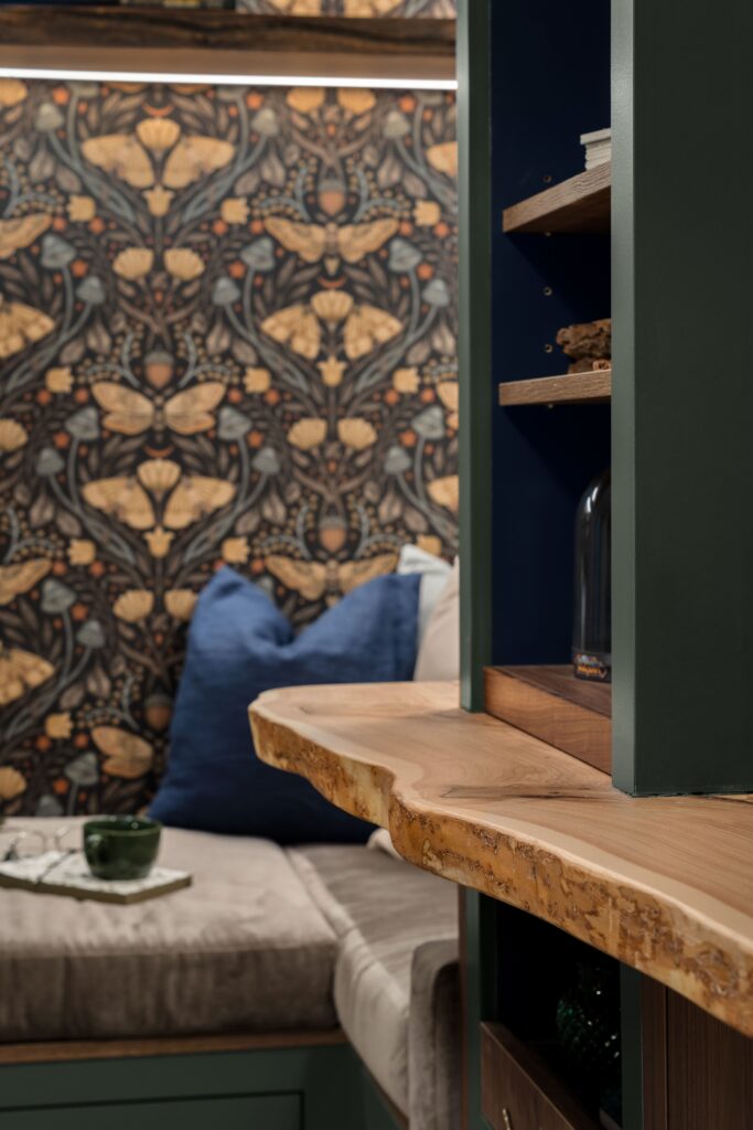 A close-up of the live-edge wood desk's natural edge, beneath built-in shelving in the reading nook.
