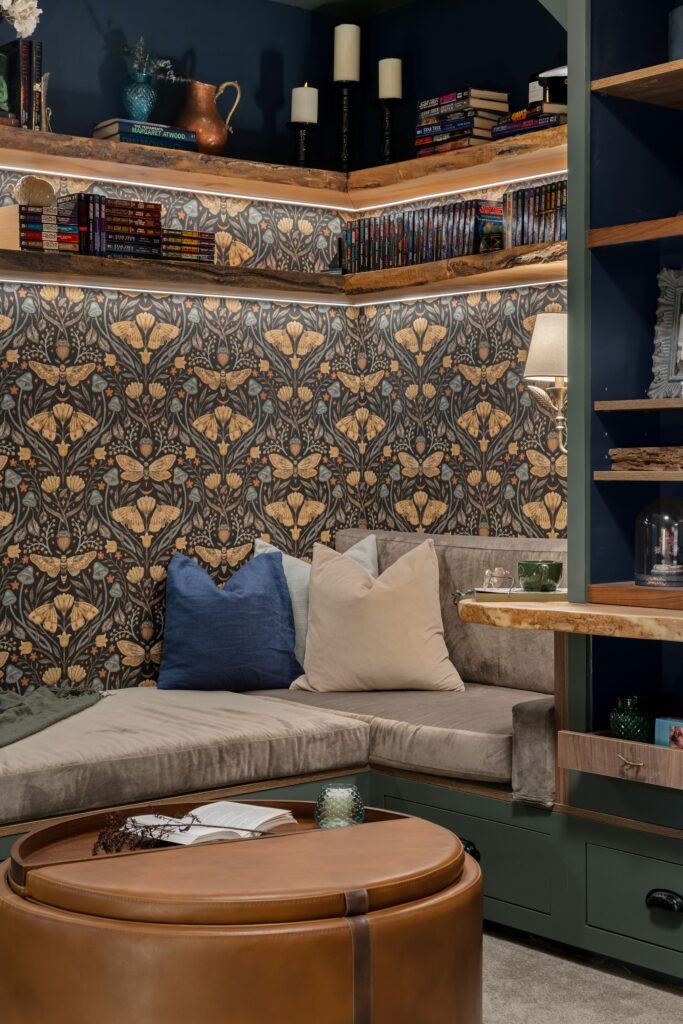 Built-in bench seating in the reading nook, styled with fluffy pillows against the dark botanical wallpaper.
